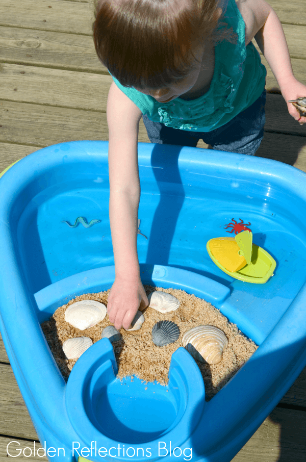 playing with beach themed water sensory table for toddlers