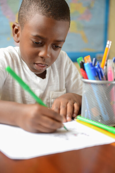 Young black boy writing.