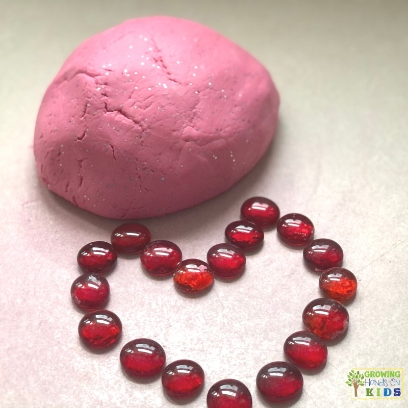 red play dough ball with red glass beads shaped in a heart. 