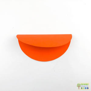 Orange circle paper folded in half for the rocking carrot paper fine motor craft.