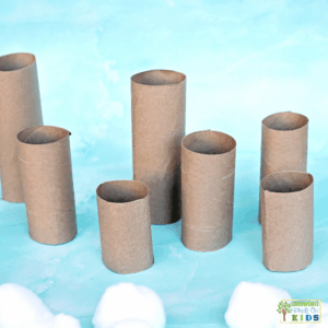 Cardboard paper rolls cut to different heights standing upright on a blue surface, ready for a snowball balance fine motor activity for kids.