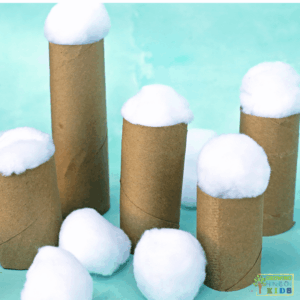 White pom pom snowballs balanced on cardboard tubes of varying heights, creating a winter-themed fine motor and balance activity setup for kids.
