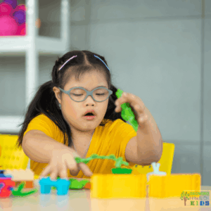 Child wearing glasses playing with colorful building toys at a table, using visual perceptual skills and hand-eye coordination during hands-on play.