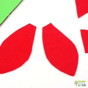 Two red felt pieces cut into ladybug wing shapes for a buttoning fine motor activity.